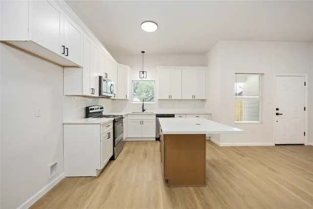 a kitchen with wooden floors and white cabinets