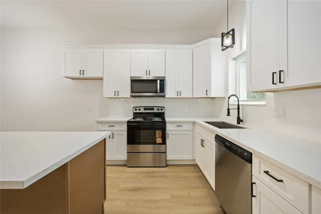 a kitchen with stainless steel appliances a stove a sink and white cabinets
