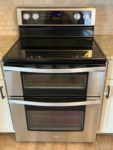 a view of a refrigerator in kitchen and an empty room with wooden floor