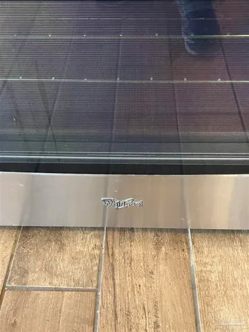 a view of a refrigerator in kitchen and an empty room with wooden floor