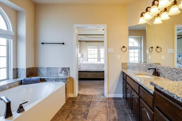 a bathroom with a tub double vanity sink and a mirror