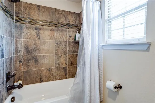 a bathroom with a bathtub a window and a shower