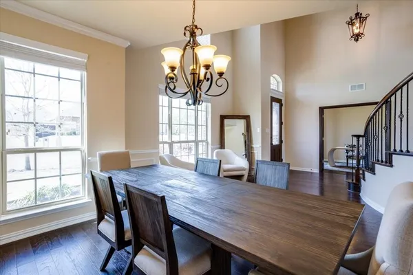 a dining room with wooden floor a chandelier a wooden table and chairs