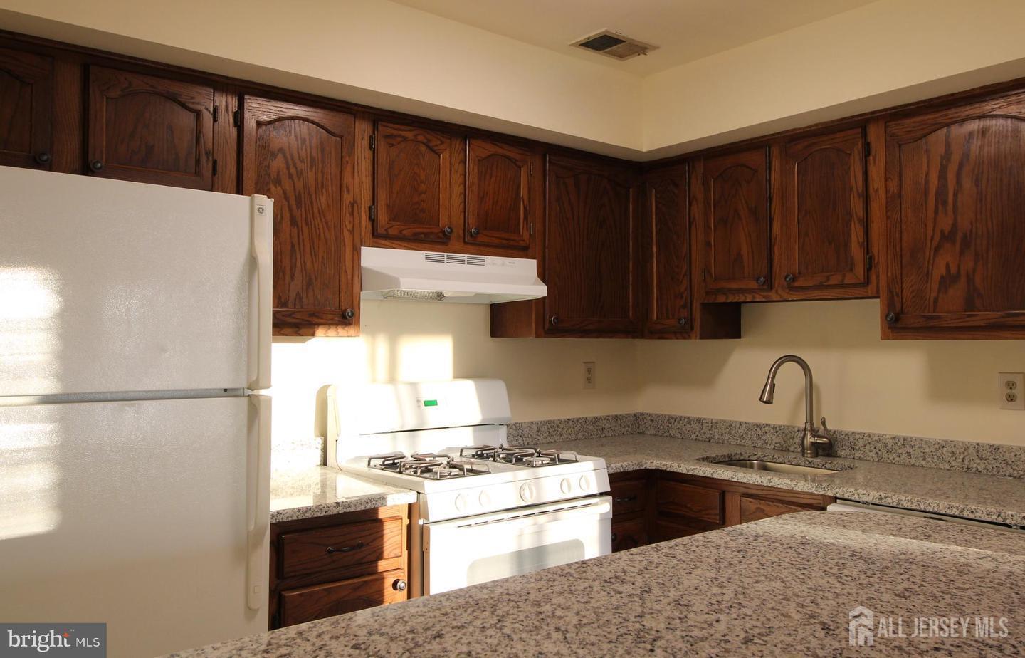 103 Claridge Court, Unit 5 Princeton, NJ 08540 - Photo 13 of 24 a kitchen with stainless steel appliances granite countertop a refrigerator stove a sink dishwasher and wooden cabinets
