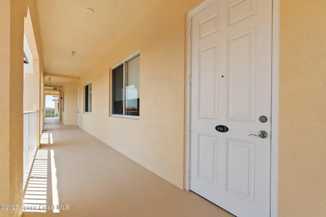 a view of a hallway with wooden floor and a bathroom