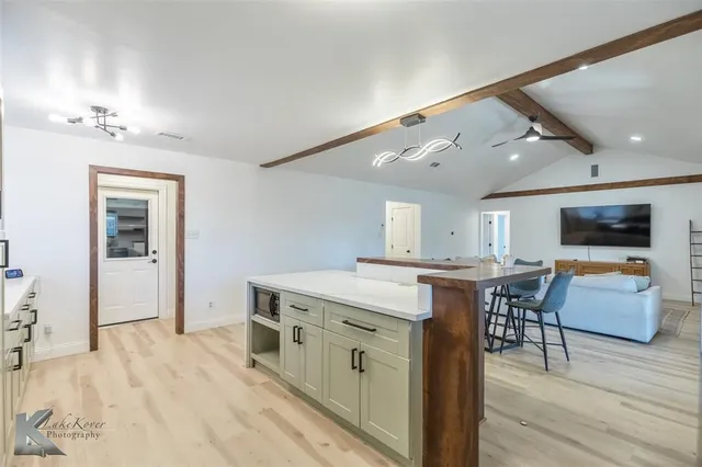 a kitchen with stainless steel appliances wooden floor and view living room