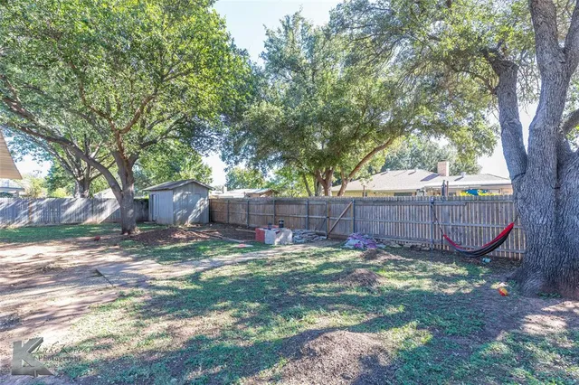 a view of a backyard with a tree and wooden fence