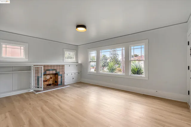 an empty room with windows and fireplace