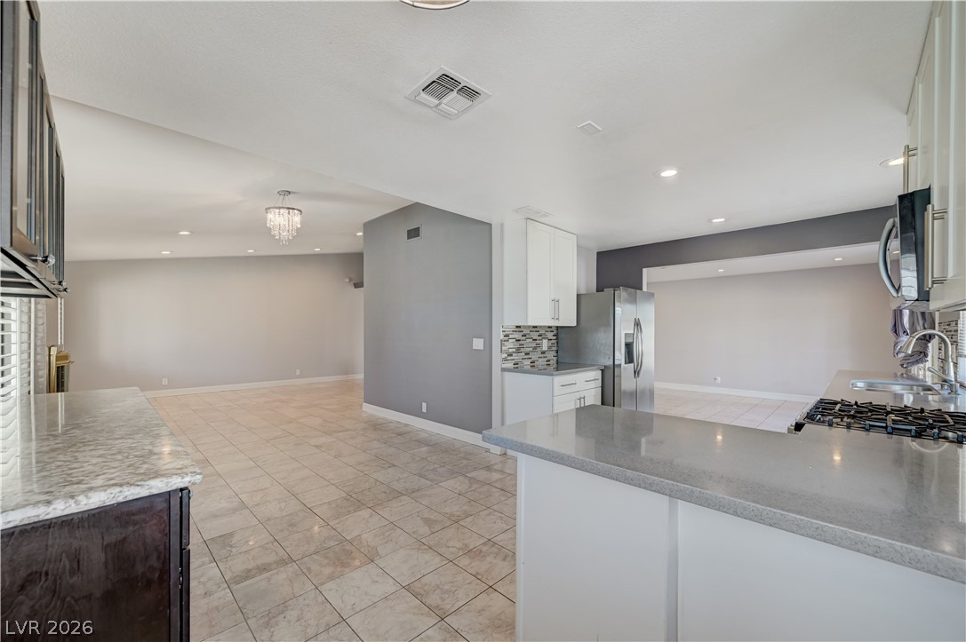 6635 Costa Brava Road Las Vegas, NV 89146 - Photo 14 of 59 A well-lit kitchen with sleek countertops and integrated appliances connects to an open living area.