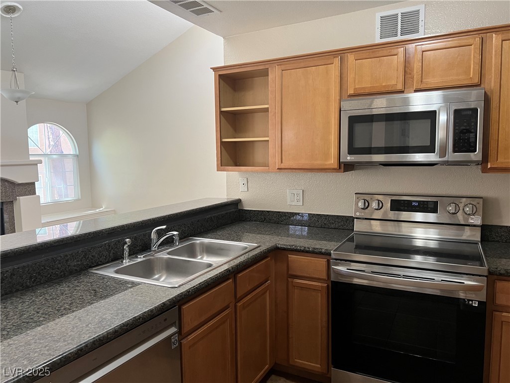 9325 West Desert Inn Road, Unit 233 Las Vegas, NV 89117 - Photo 3 of 10 Kitchen featuring appliances with stainless steel finishes, open shelves, dark countertops, brown cabinets, and lofted ceiling