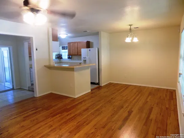 a view of kitchen and empty room with wooden floor