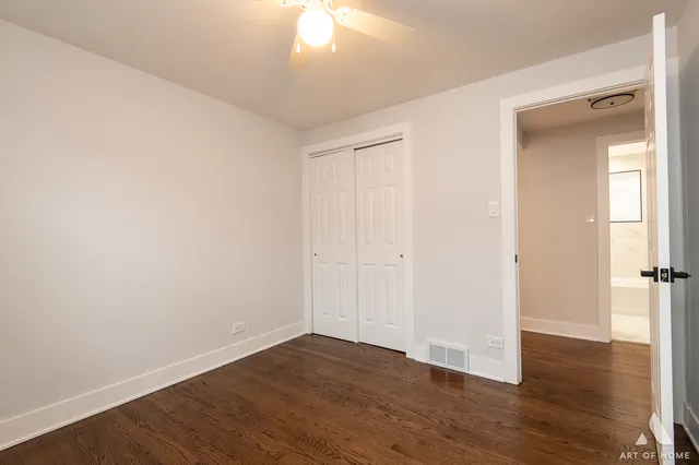 an empty room with wooden floor and fan