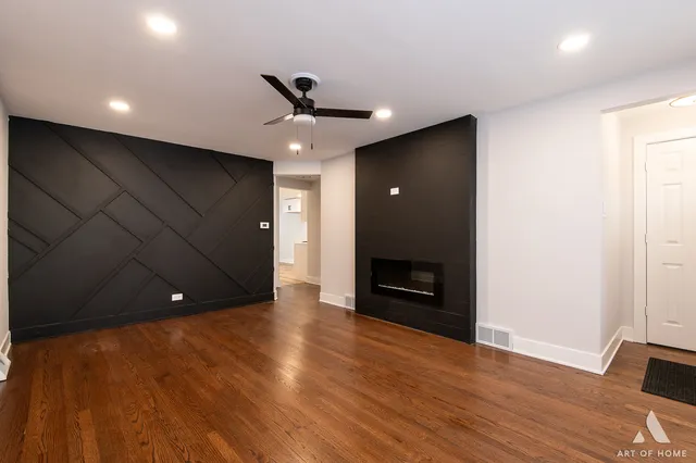 a view of an empty room with wooden floor and a ceiling fan