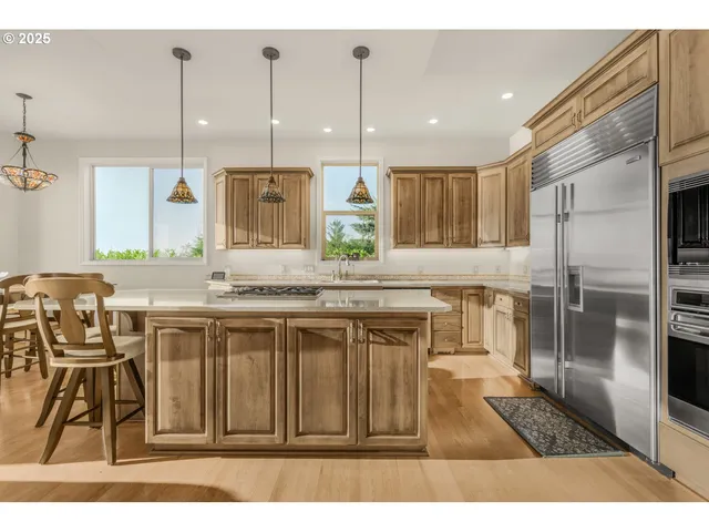 a kitchen with kitchen island granite countertop a refrigerator a sink a stove and chairs