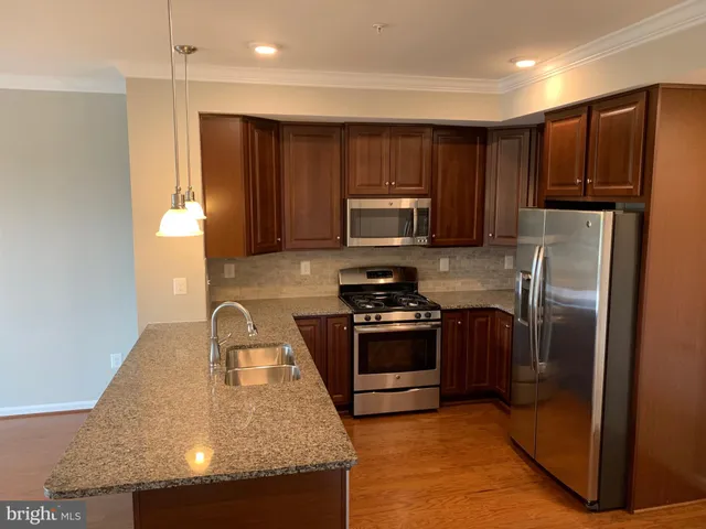 a kitchen with kitchen island granite countertop stainless steel appliances and wooden cabinets