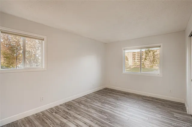 a view of empty room with wooden floor and fan