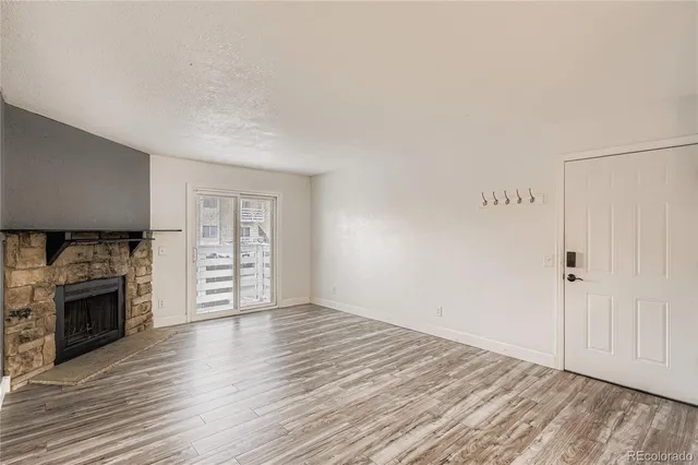 an empty room with wooden floor fireplace and windows