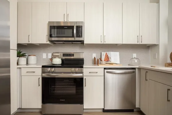 a kitchen with stainless steel appliances granite countertop a stove a microwave and a white cabinets