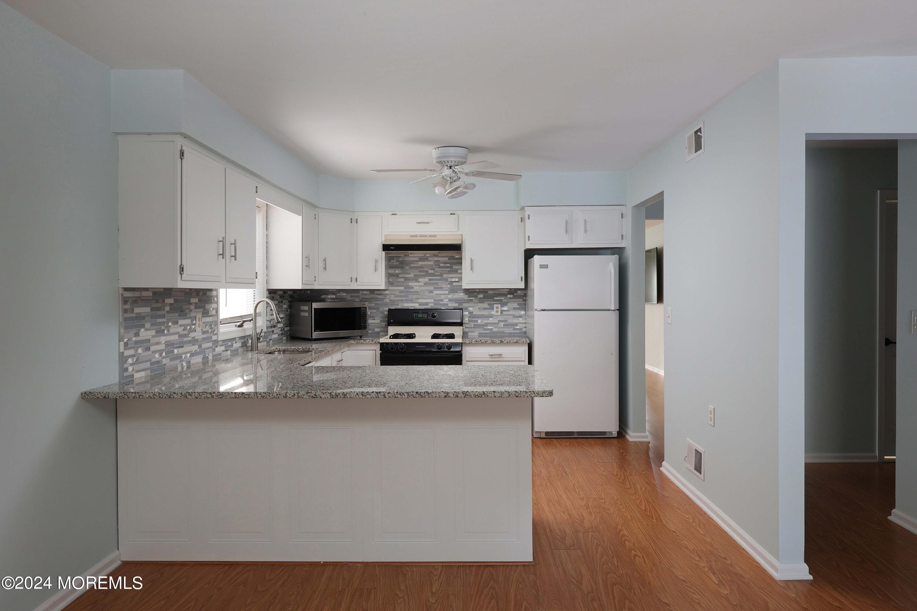 98 Greenbriar Boulevard Brick, NJ 08724 - Photo 17 of 31 a kitchen with stainless steel appliances granite countertop a refrigerator a stove a sink and white countertops with wooden floor