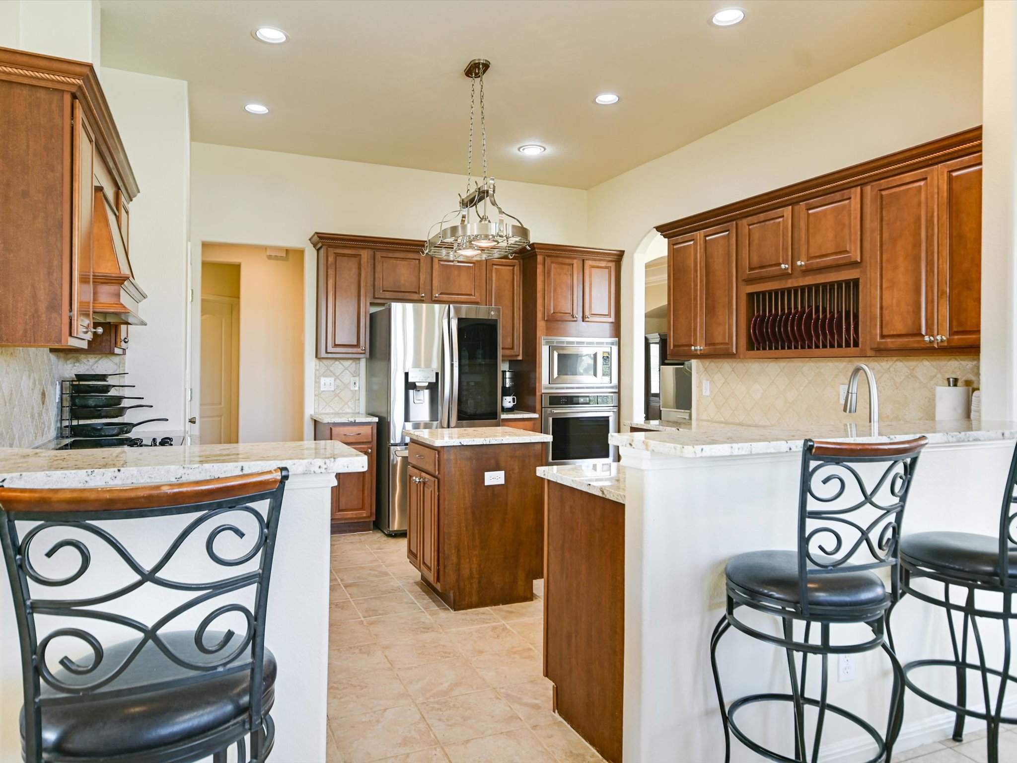10111 Baxter Lane Austin, TX 78736 - Photo 14 of 35 a kitchen with stainless steel appliances kitchen island granite countertop a stove a refrigerator a sink a dining table and chairs with wooden floor