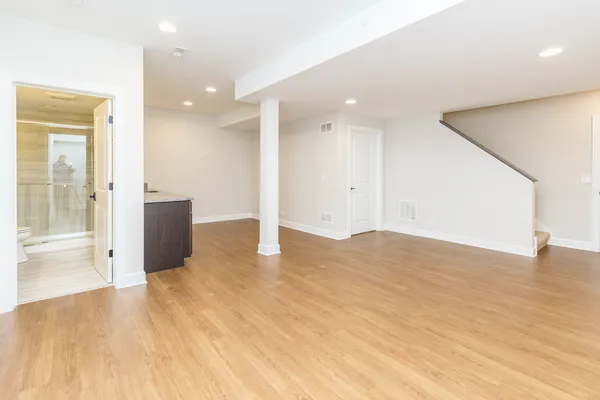 a view of an empty room with wooden floor and a bathroom