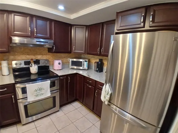 a kitchen with stainless steel appliances granite countertop a refrigerator a sink dishwasher and wooden cabinets with wooden floor