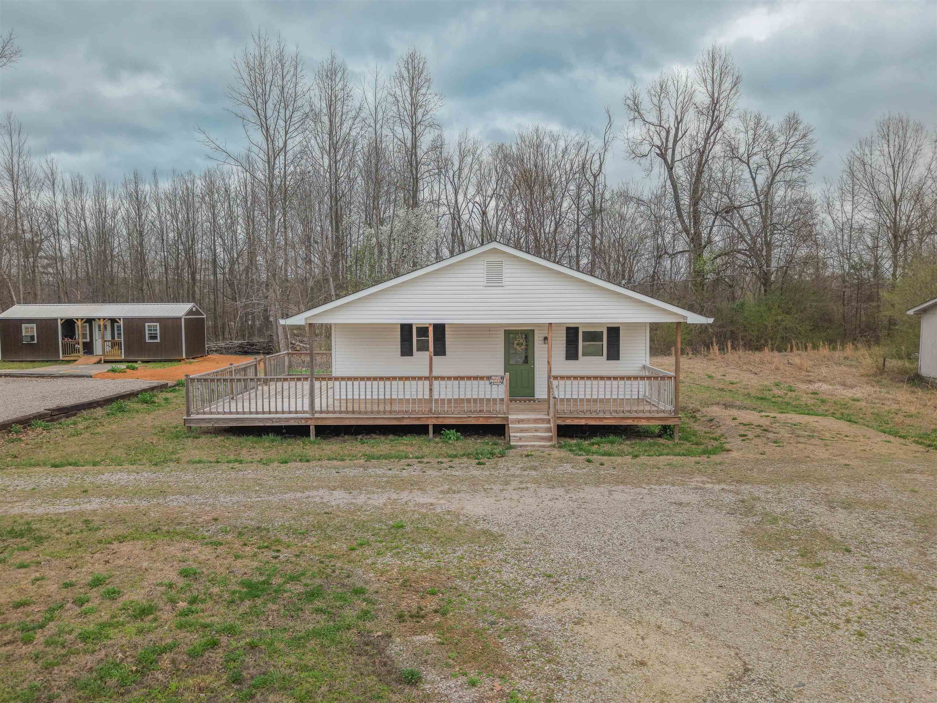 View of front of property featuring covered porch and an outbuilding