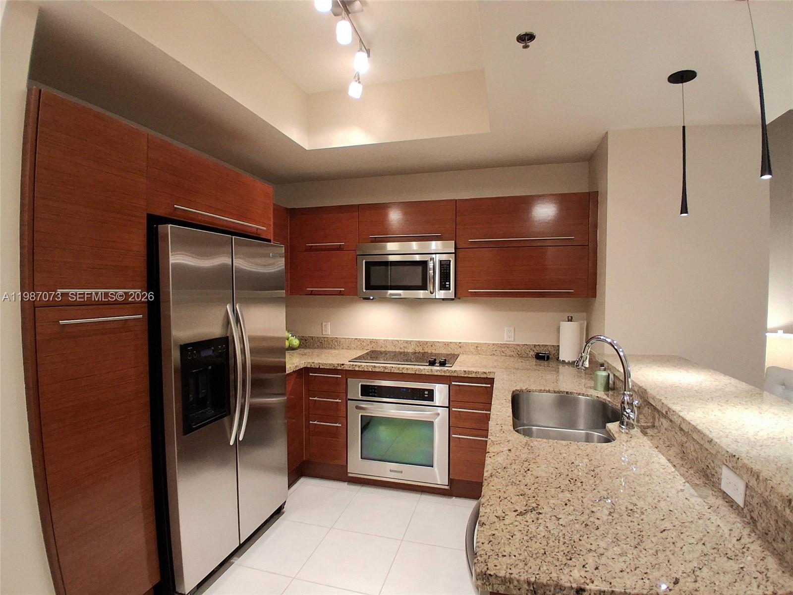 2641 North Flamingo Road, Unit 2607N Sunrise, FL 33323 - Photo 6 of 69 a kitchen with stainless steel appliances granite countertop a refrigerator a oven a sink with a dining table and chairs