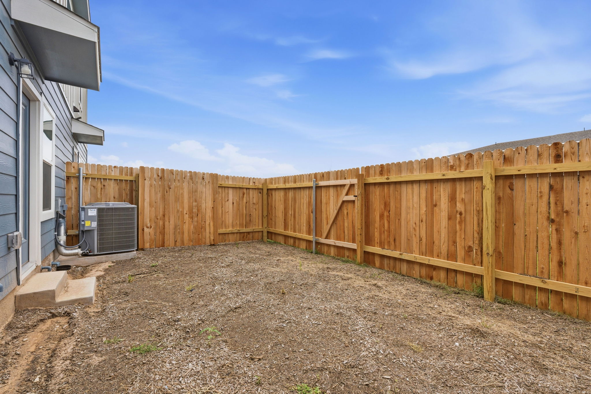 164 Cinnabar Lane, Unit 4 Kyle, TX 78640 - Photo 22 of 23 Fenced backyard featuring a wood privacy fence with gate, exterior siding, and a concrete step leading to an exterior door