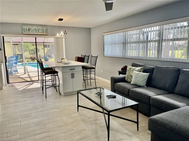 a living room with furniture a large window and wooden floor