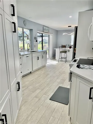 a large white kitchen with sink and refrigerator