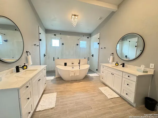 a spacious bathroom with double vanity sink a mirror a bathtub and a shower