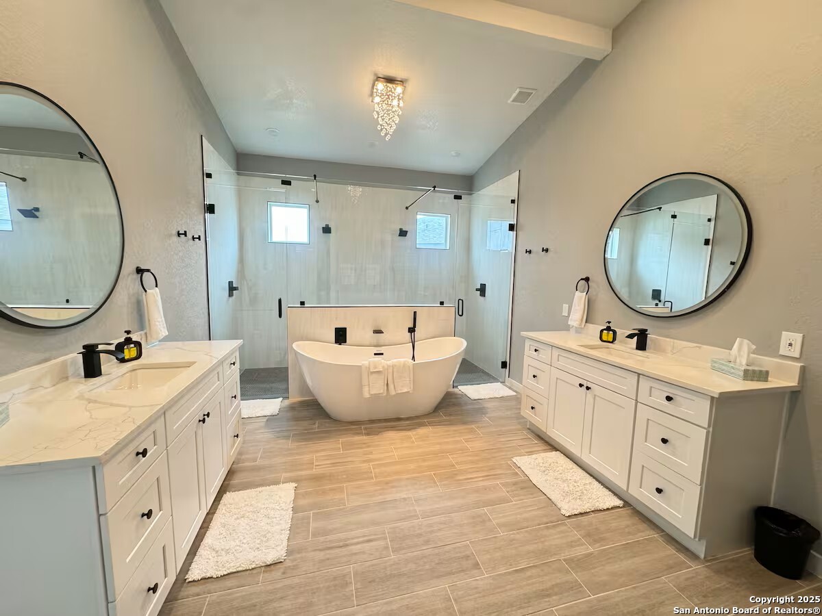 1652 Rimrock Cove Spring Branch, TX 78070 - Photo 13 of 26 a spacious bathroom with double vanity sink a mirror a bathtub and a shower