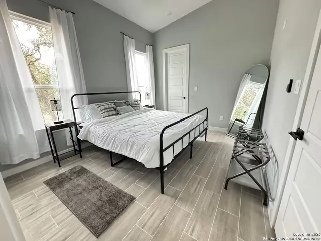 a bedroom with a bed lamp on desk and a window