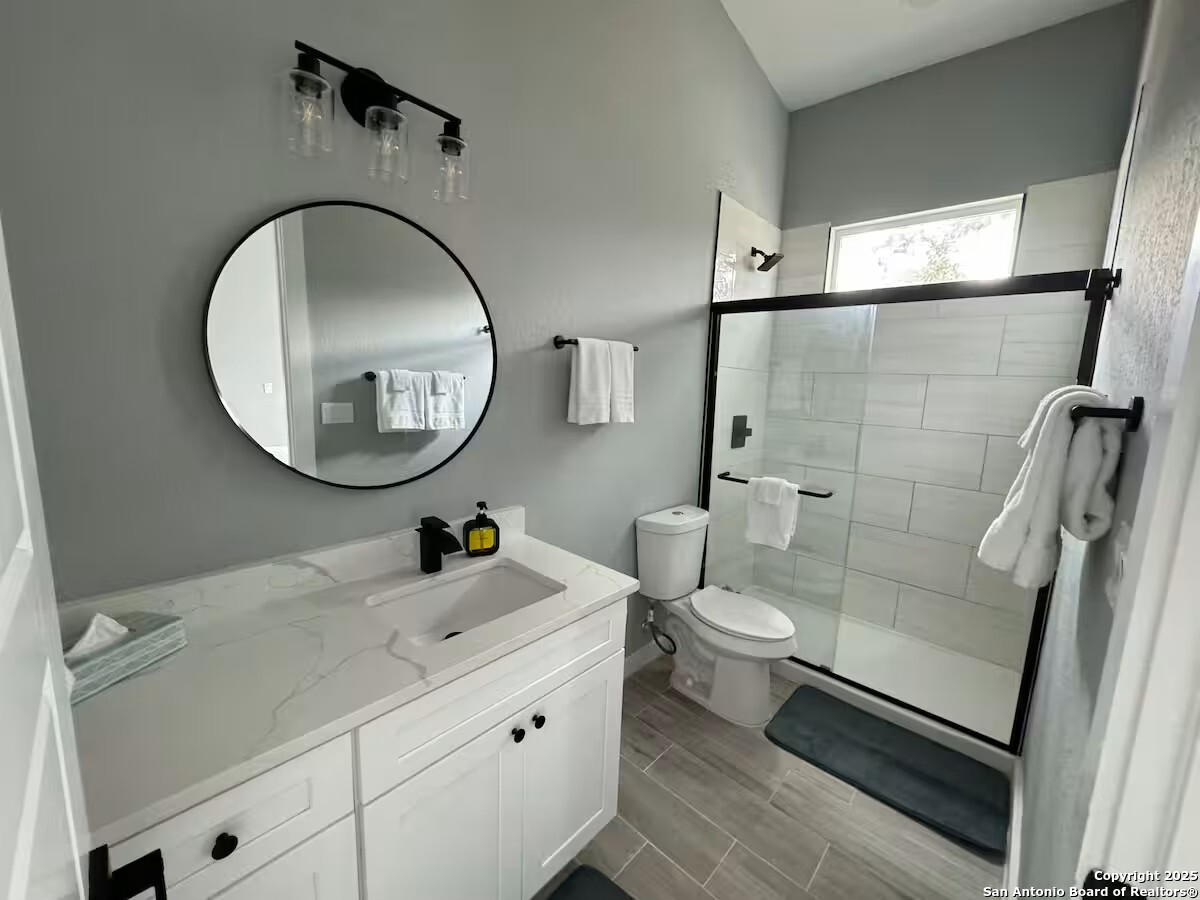 1652 Rimrock Cove Spring Branch, TX 78070 - Photo 17 of 26 a bathroom with a toilet a sink and a mirror