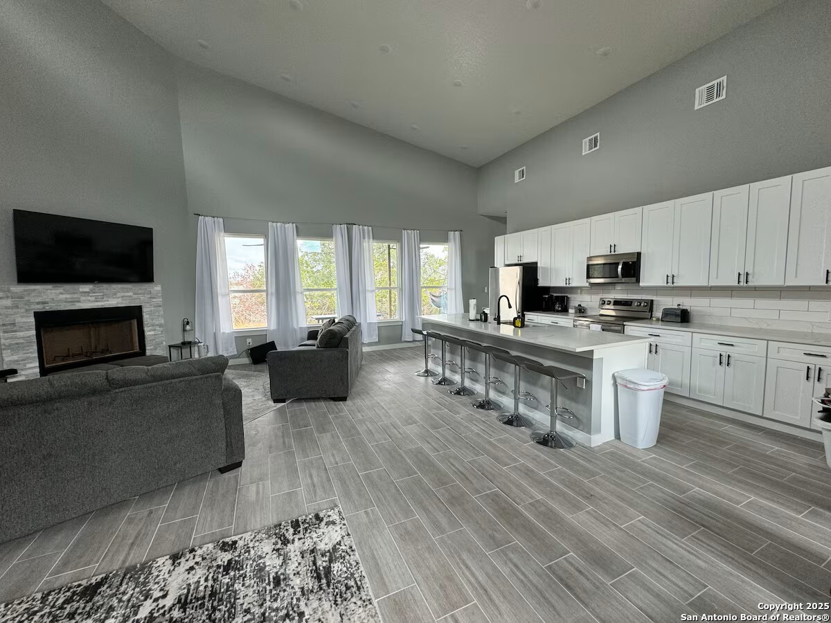 1652 Rimrock Cove Spring Branch, TX 78070 - Photo 8 of 26 a kitchen with furniture a flat screen tv and a fireplace