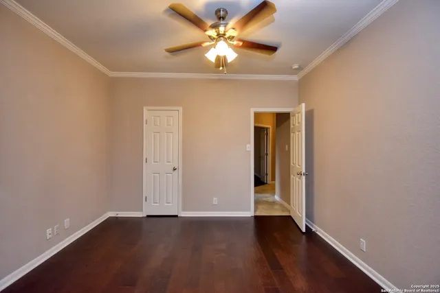 an empty room with wooden floor and a ceiling fan