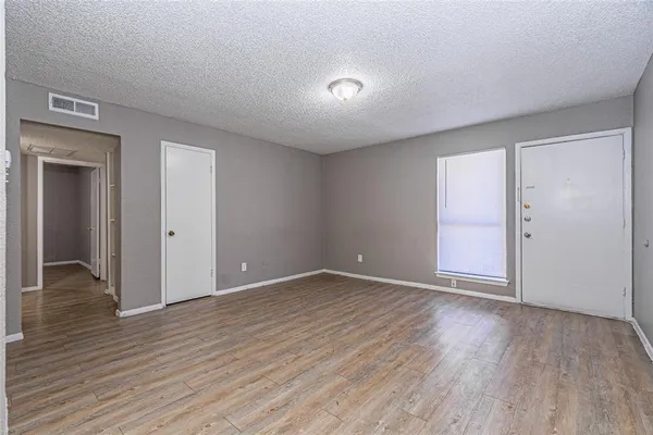 a view of an empty room with wooden floor and closet
