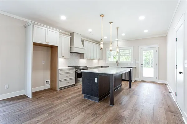 a kitchen with stainless steel appliances granite countertop a wooden floors and white cabinets