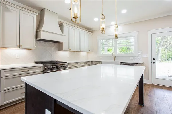 a large kitchen with granite countertop a sink a stove and a refrigerator