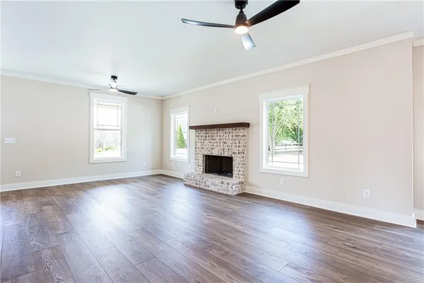 an empty room with wooden floor fireplace and windows