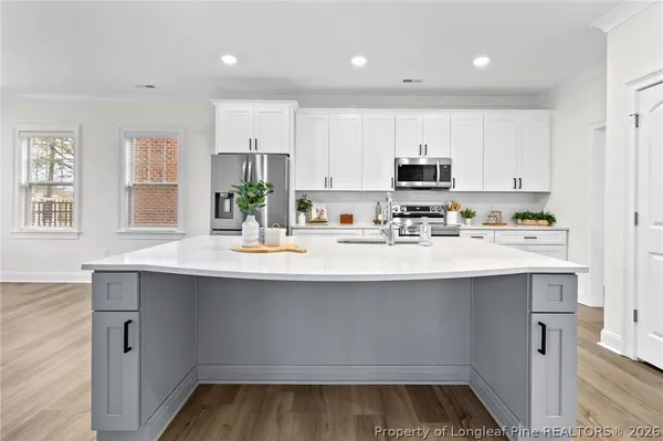 a kitchen with kitchen island white cabinets appliances and sink