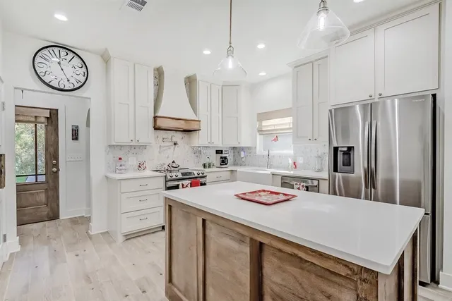 a kitchen with kitchen island a stove a refrigerator a sink and a stove with wooden floor