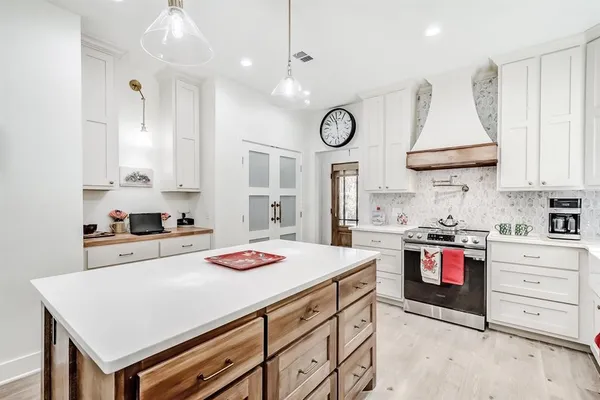 a kitchen that has a lot of white cabinets and stainless steel appliances