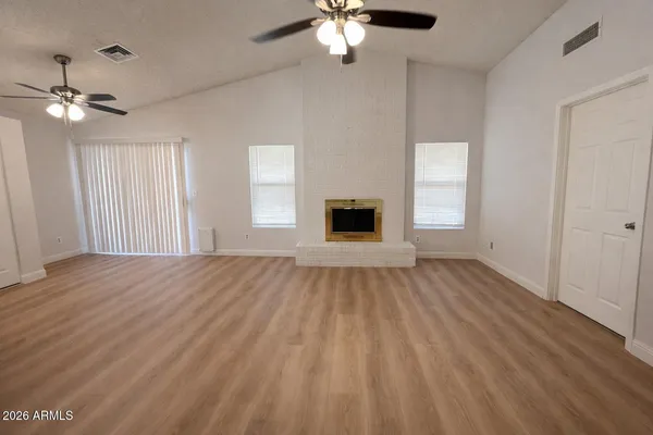 a view of empty room with wooden floor and fan