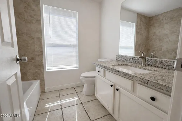 a bathroom with a granite countertop sink a toilet and a mirror