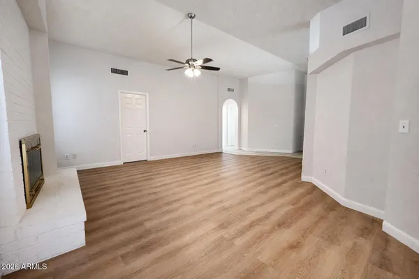 a view of an empty room with a window and wooden floor