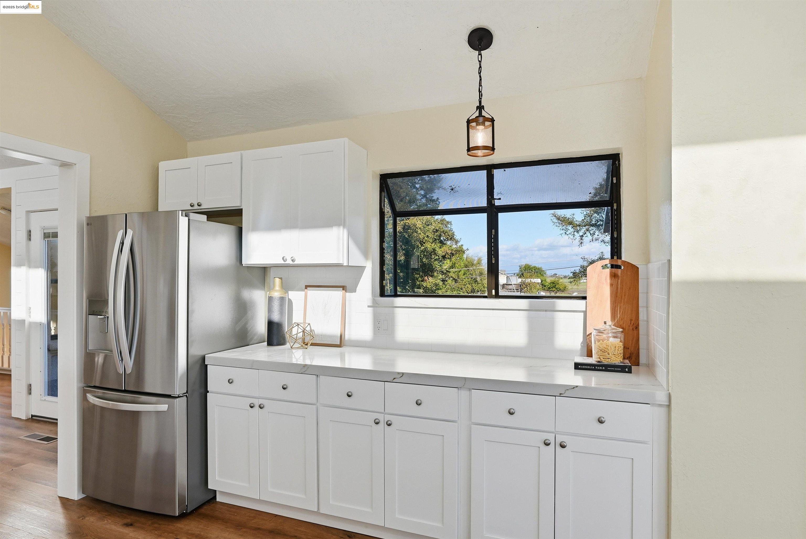 2796 Taylor Road Bethel Island, CA 94511 - Photo 13 of 49 Kitchen featuring white cabinetry, light countertops, decorative light fixtures, lofted ceiling, and stainless steel fridge with ice dispenser
