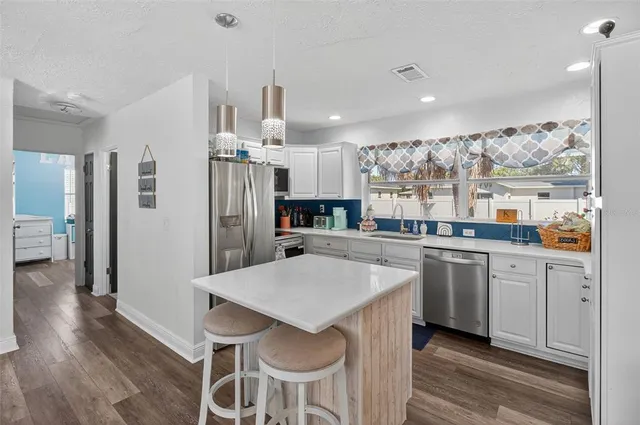 a kitchen with stainless steel appliances a dining table chairs and refrigerator