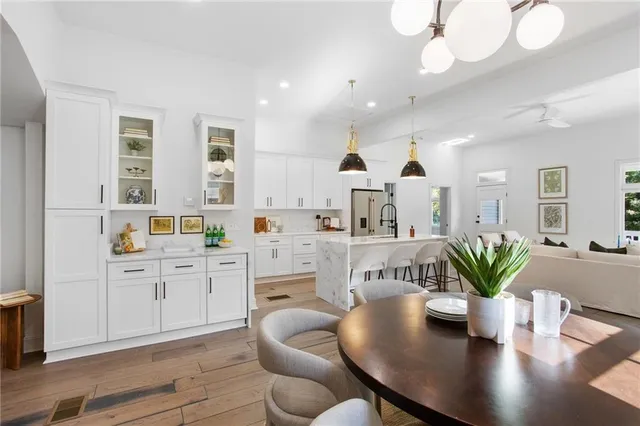 a kitchen with white cabinets stainless steel appliances and dining table